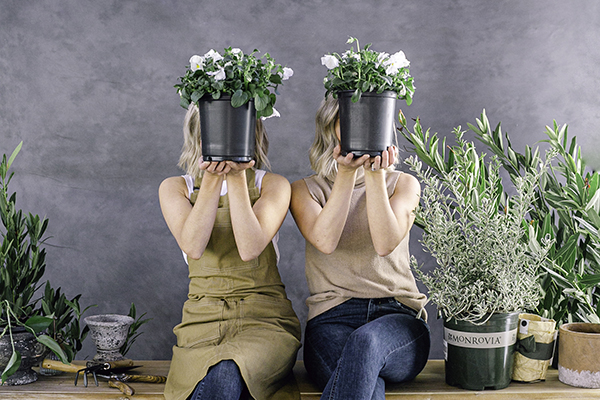 Those plant ladies, twin sisters, covering their face with potted flowers
