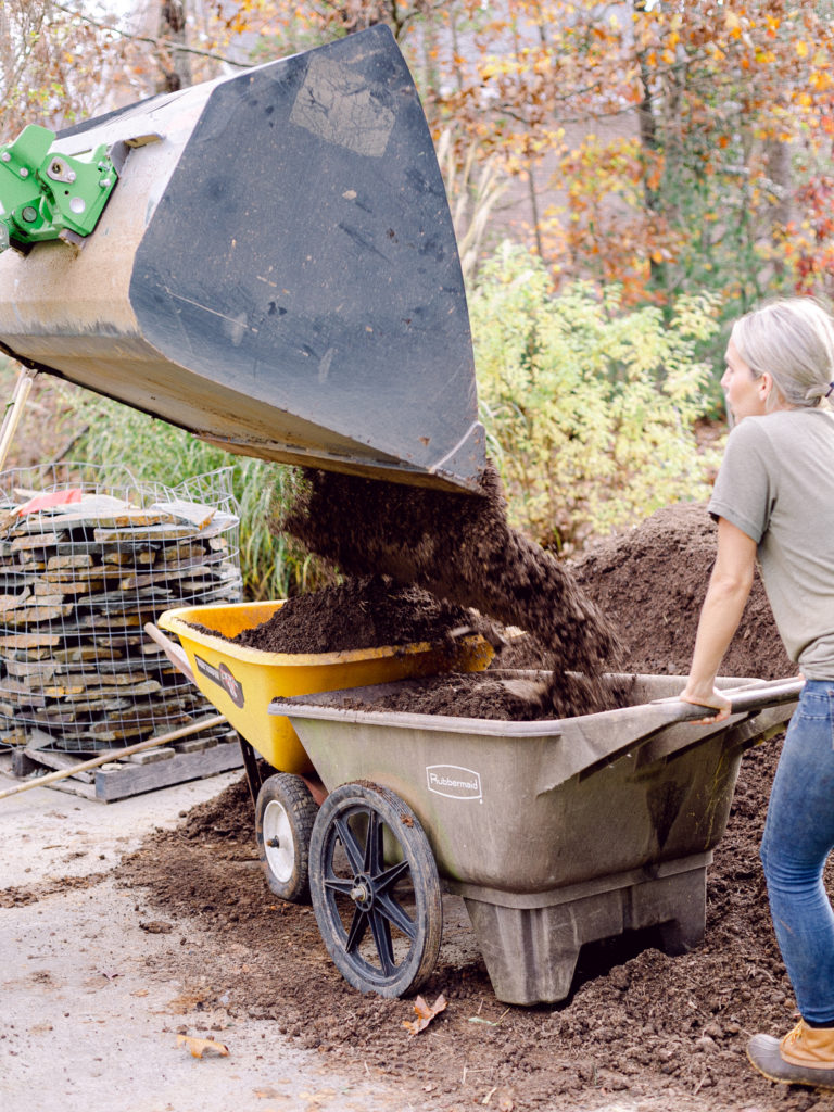 The Avant Loader 630 dumping mulch into two wheel barrows on Those Plant Ladies landscape installation.