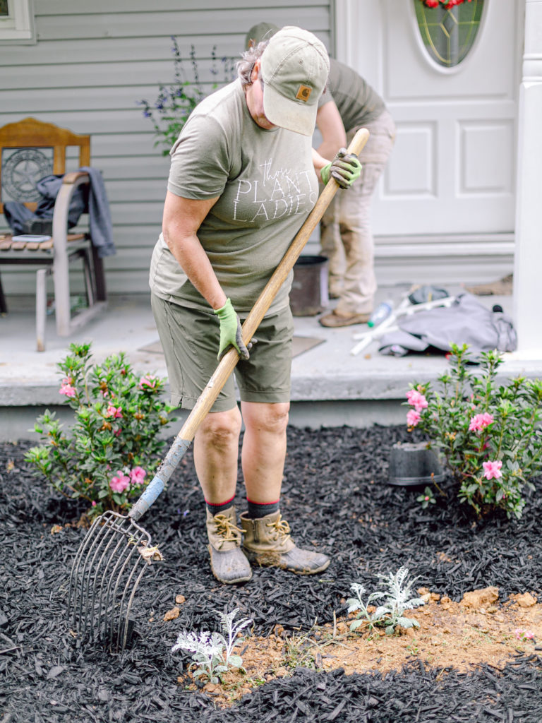 A member of Those Plant Ladies spreading mulch at an installation.