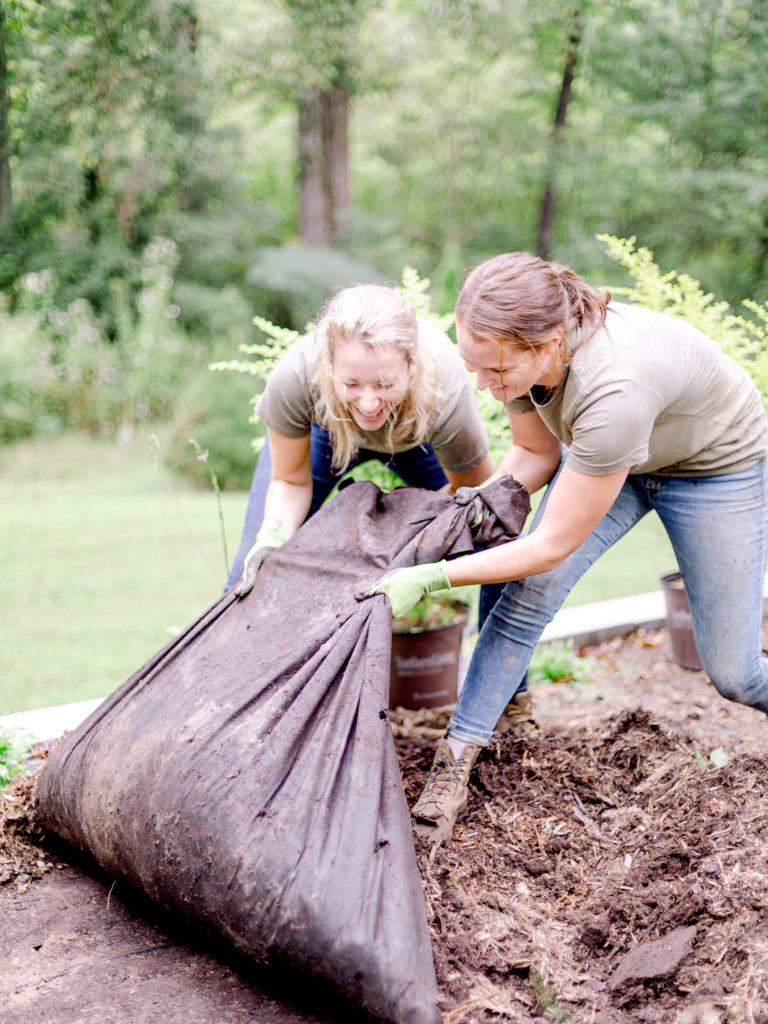 Members of Those Plant Ladies removing old mulch at an installation job site.