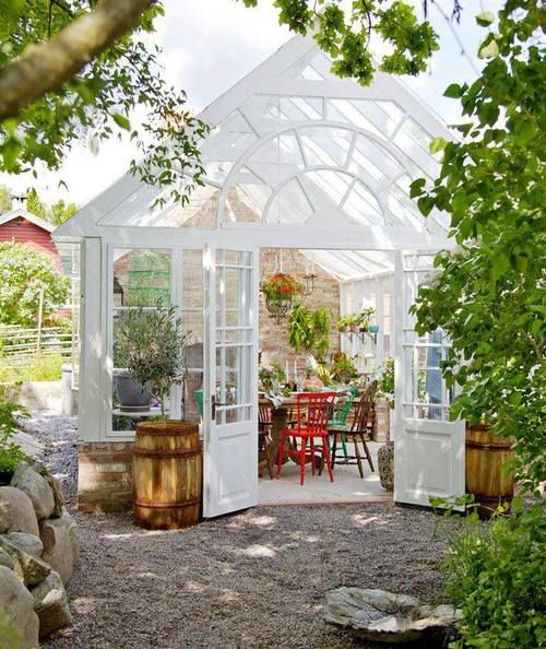 White greenhouse with the exterior doors open; sitting area inside.