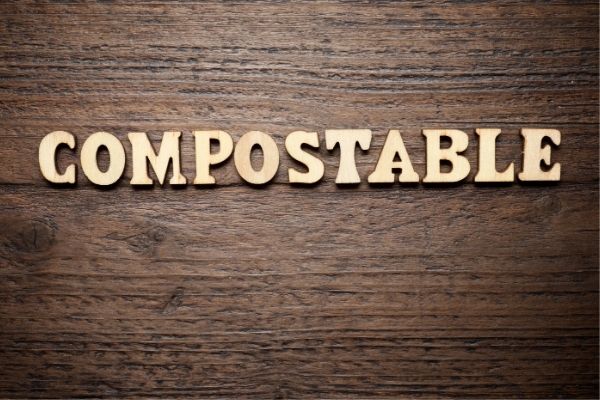 Wooden background with wood letters spelling out COMPOSTABLE.