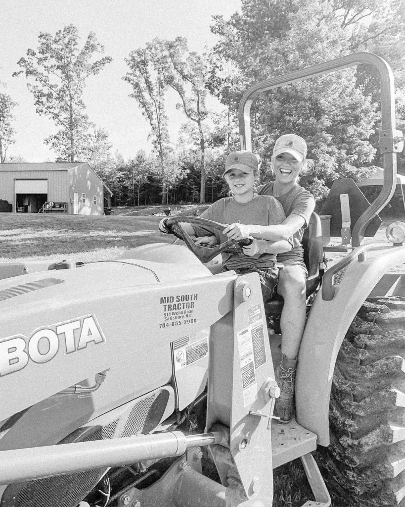 Fawn of Those Plant Ladies teaching a young girl to drive the Kubota tractor.