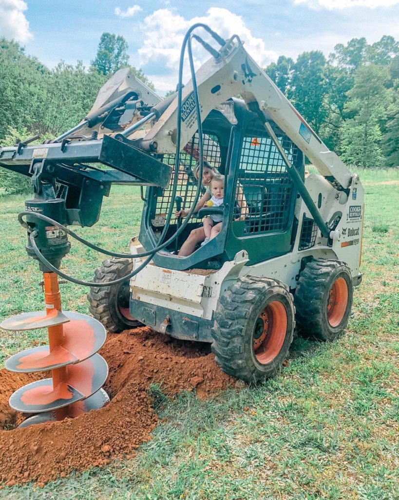 Fawn of Those Plant Ladies driving a bobcat with her son in her lap.