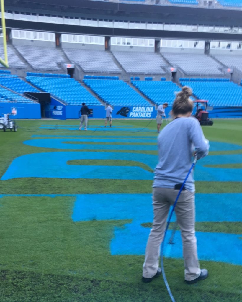 Fawn of Those Plant Ladies painting the end zone at the Panthers' stadium.