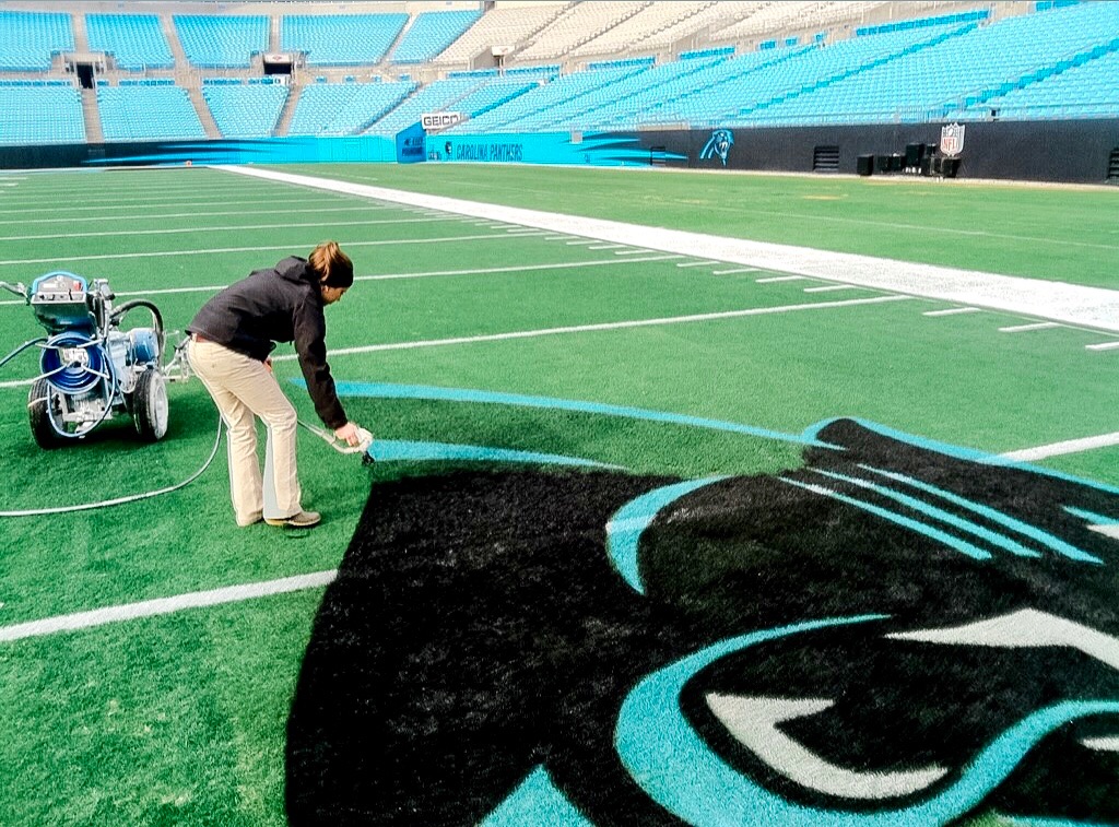 Fawn of Those Plant Ladies painting the lines of the logo for the Carolina Panthers.