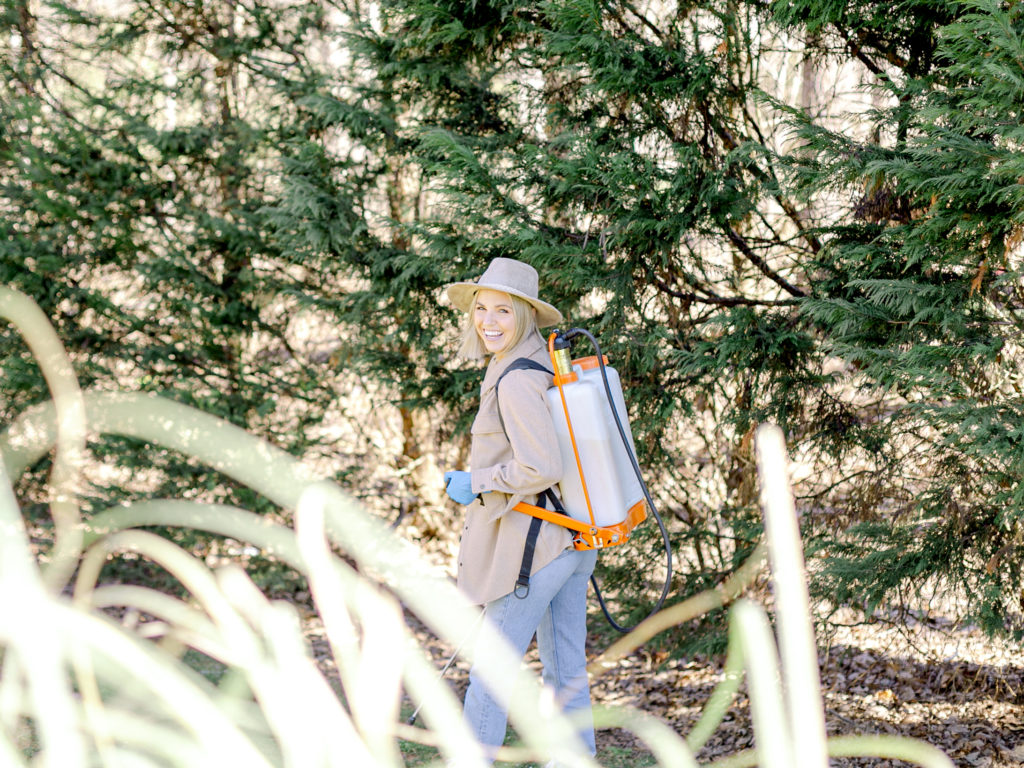 Fawn of Those Plant Ladies using a backpack sprayer to apply pre-emergent to prevent weeds in the grass.